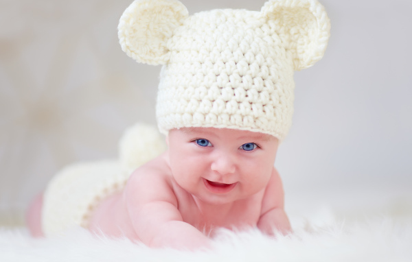 Голубоглазый грудной ребенок в белой вязаной шапке с ушками