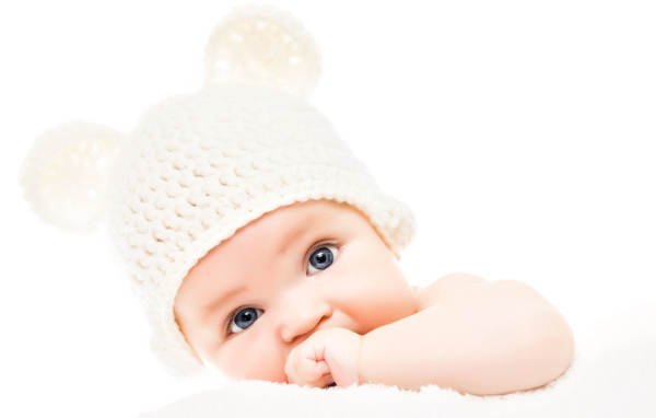 Голубоглазый младенец с белой шапке с ушками на белом фоне