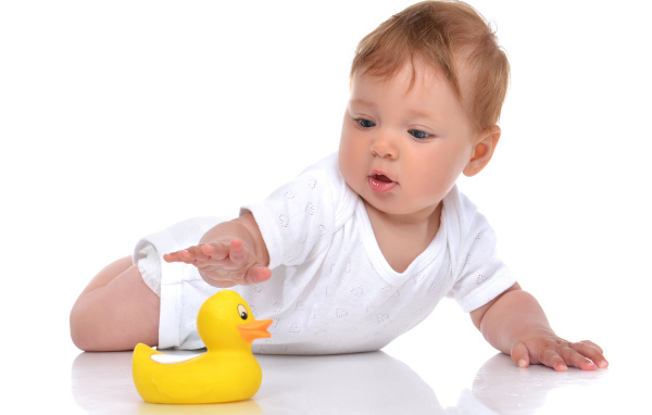Грудной ребенок с желтой резиновой уточкой на белом фоне