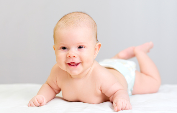 Милый улыбающийся ребенок на сером фоне