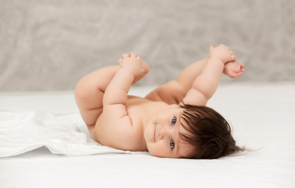 Забавный младенец держится руками за ноги 