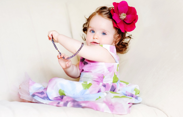 Маленькая голубоглазая девочка с красным цветком в волосах