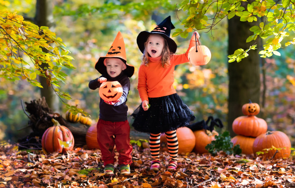 Маленькие мальчик и девочка в костюмах с тыквами на Хэллоуин