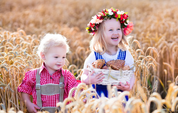 Маленькие мальчик и девочка на поле пшеницы с корзиной свежей выпечки