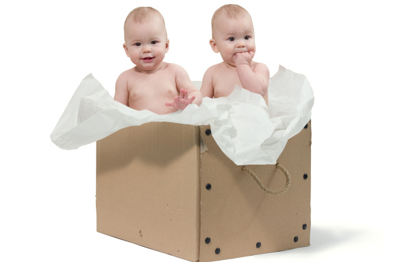 Маленькие дети сидят в картонной коробке с бумагой
