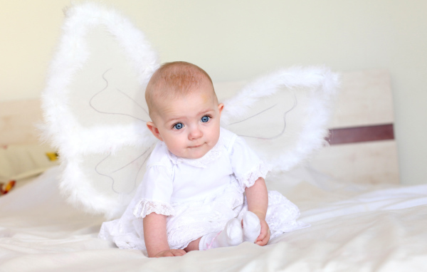 Маленькая девочка в красивом белом платье с крыльями