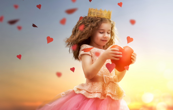 Маленькая девочка в костюме принцессы с красным сердцем в руках