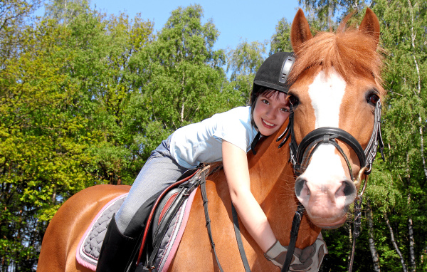Маленькая девочка сидит на коричневой лошади