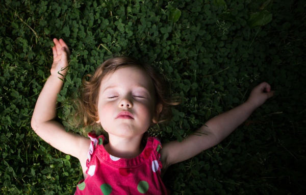 Маленькая девочка спит на зеленой траве 