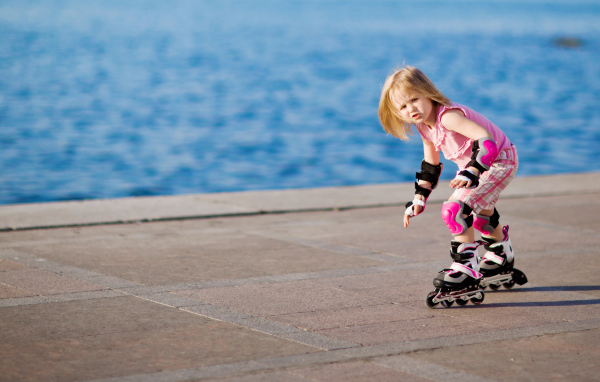 Маленькая девочка катается на роликах на побережье