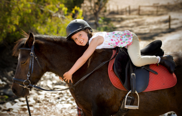 Маленькая девочка в шлеме верхом на пони