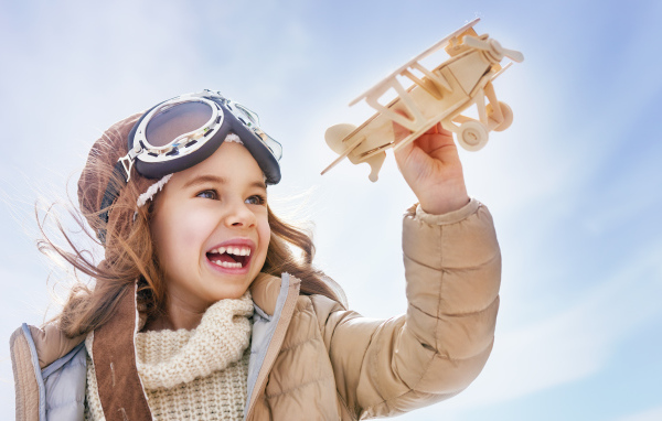 Маленькая улыбающаяся девочка с самолетом в руках 