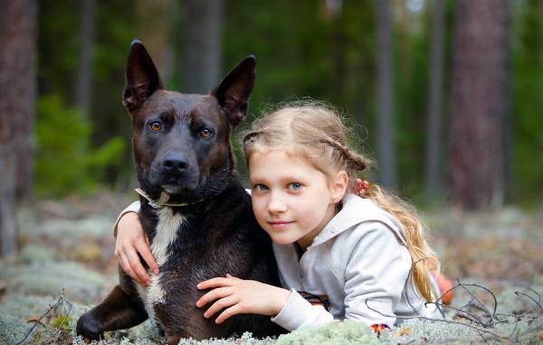 Милая голубоглазая девочка с большой черной собакой