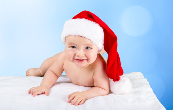 Улыбающийся грудной ребенок в новогодней шапке
