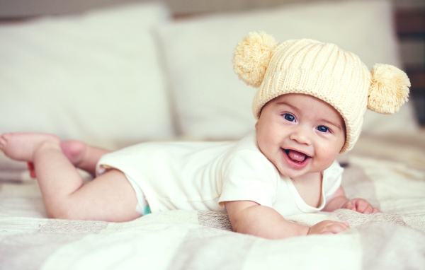 Улыбающийся грудной ребенок в забавной вязаной шапке