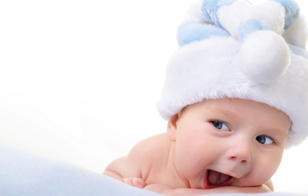 Улыбающийся грудной ребенок в голубой новогодней шапке