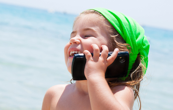 Улыбающаяся девочка в зеленом платке разговаривает по телефону