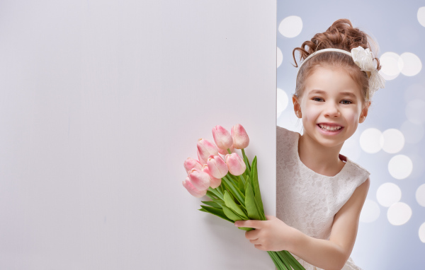 Улыбающаяся маленькая девочка с букетом розовых тюльпанов