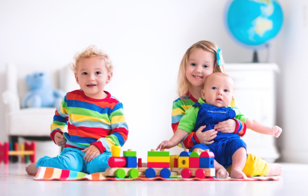 Три ребенка играют с игрушечным поездом