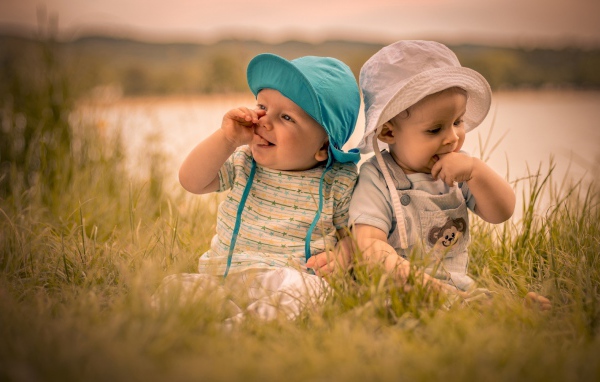 Два милых малыша в зеленой траве летом 