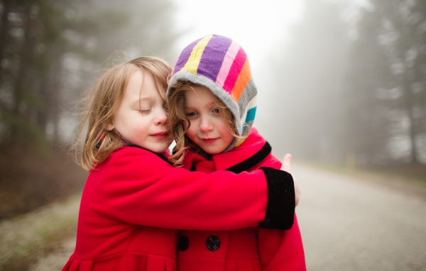 Две маленькие девочки обнимают друг друга 