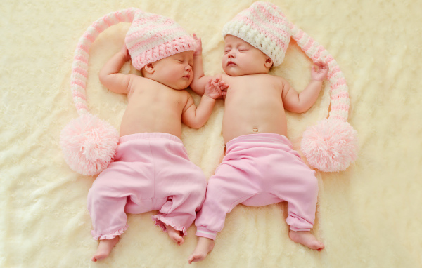 Два спящих грудных ребенка в розовых костюмах