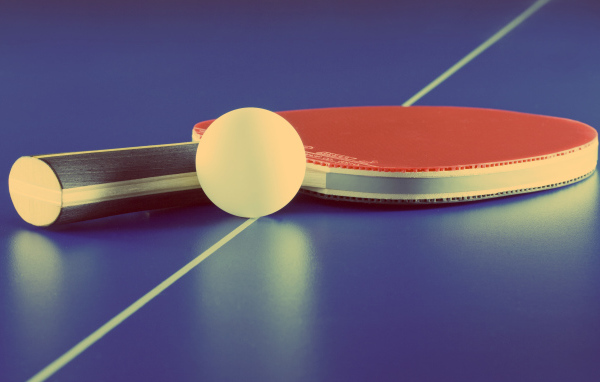 Ракетка для настольного тенниса и мяч на фиолетовом столе 