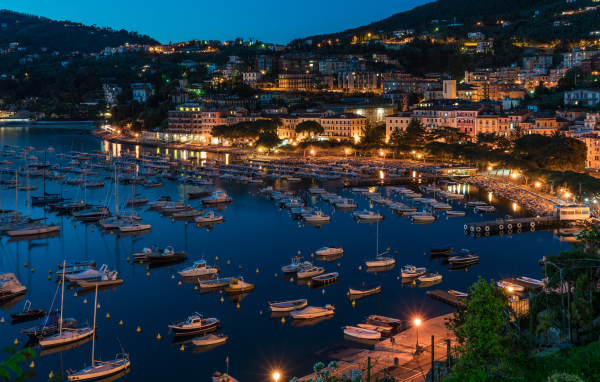 Panorama of a night city and a boat on the quay off the coast, Liguria. Italy