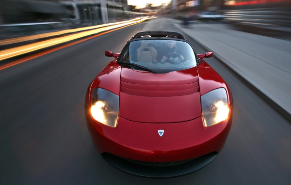 Красный электромобиль Tesla Roadster на трассе 