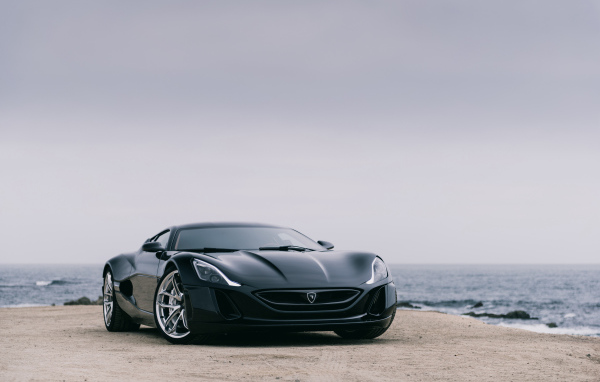 Черный спортивный автомобиль Rimac Concept One на фоне океана