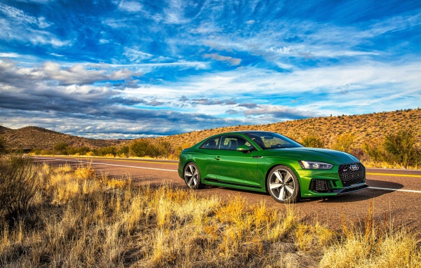 Зеленый автомобиль Audi RS5 на фоне красивого неба 