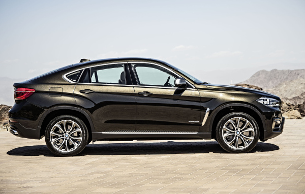 Черный автомобиль BMW X6, 2018 года вид сбоку