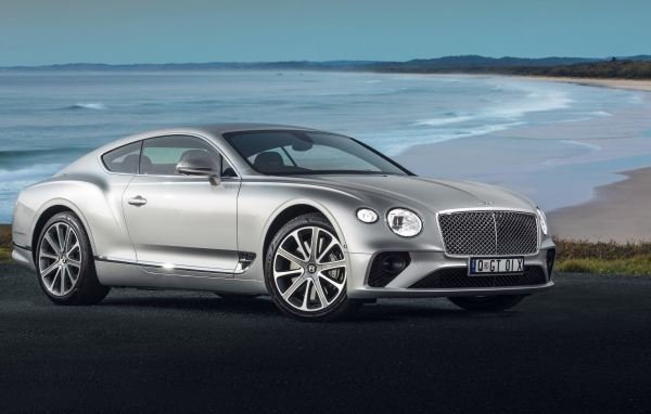 Серебристый автомобиль Bentley Continental GT 2018 года на фоне океана 