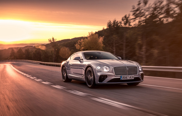 Серебристый автомобиль Bentley Continental GT 2018 года на фоне заката
