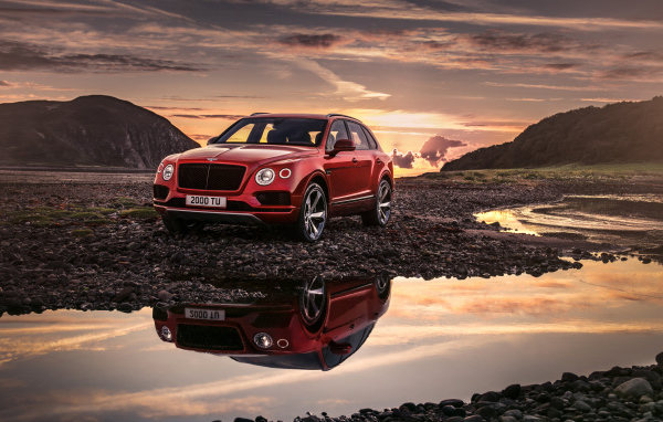 Красный автомобиль Bentley Bentayga V8, 2018 года на фоне заката 