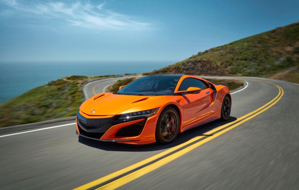 Оранжевый автомобиль Honda NSX на трассе под голубым небом