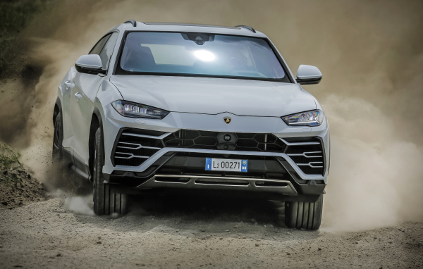 Белый автомобиль Lamborghini Urus  2018 года едет по дороге 