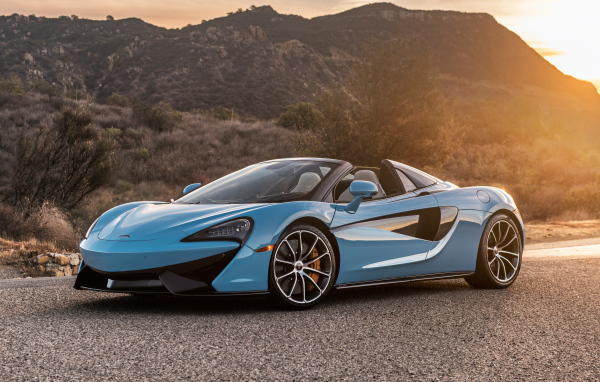 Голубой спортивный автомобиль  McLaren 570S Spider, 2018 на фоне солнца