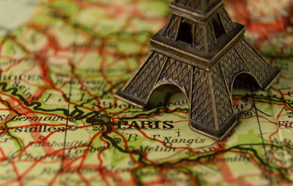 Маленькая статуэтка Эйфелева башня стоит на карте