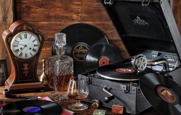 Старый граммофон с виниловыми пластинками, часами и коньяком на столе