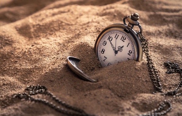 Карманные часы на цепочке в песке 