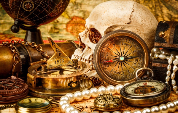 Череп, бинокль, компас, жемчуг и старинные часы на столе