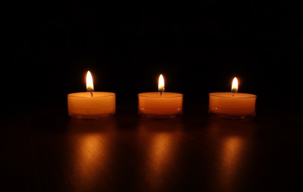 Три зажженные свечи на черном фоне