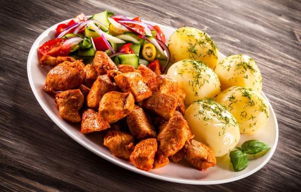 Вареный картофель с мясом и салатом на тарелке