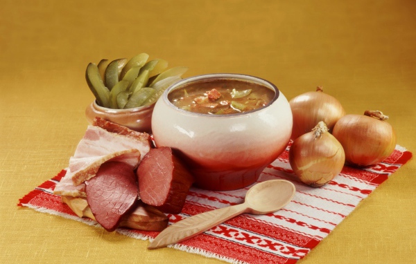 Борщ на столе с мясом, солеными огурцами и луком
