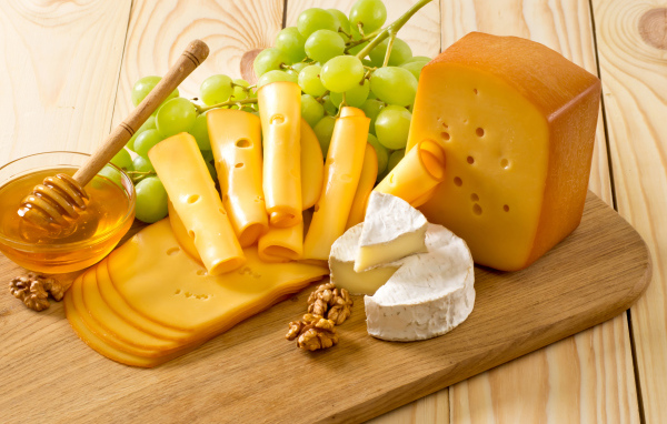 Cheese on the table with white grapes, honey and nuts