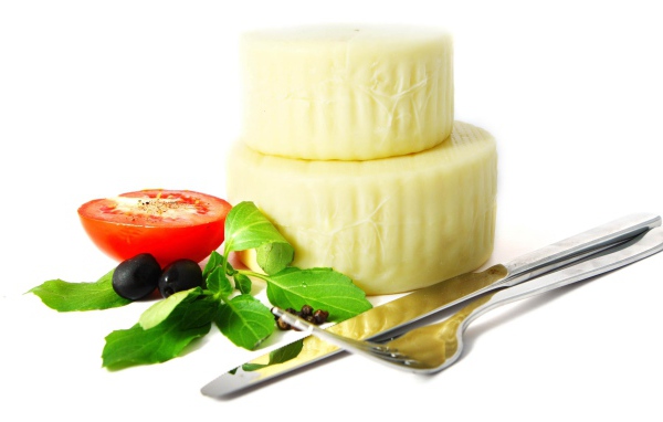 Сыр с помидором, столовыми приборами, оливками и зеленью на белом фоне