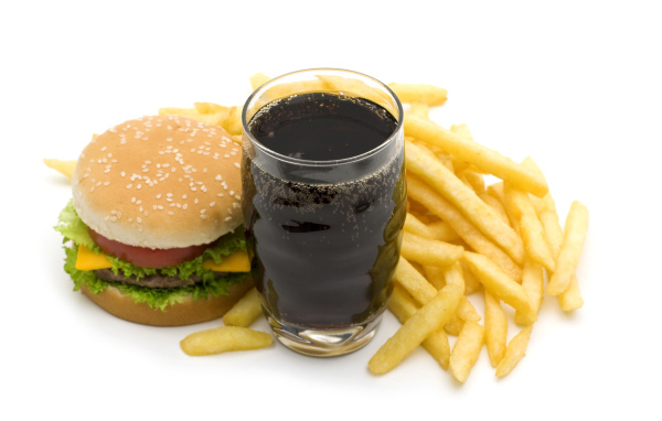 Кола в стакане на столе гамбургером и картофелем фри на белом фоне
