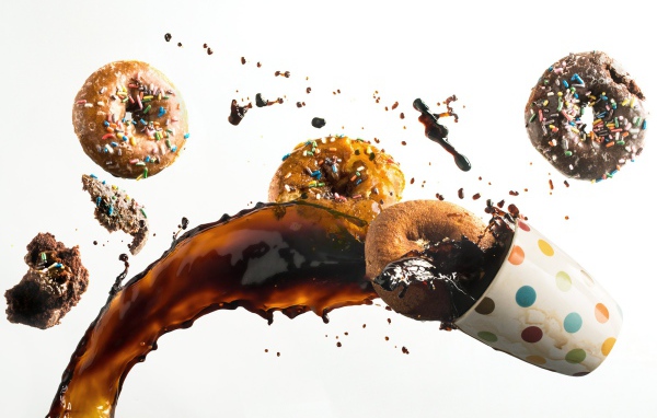 Пончики с чашкой кофе на белом фоне