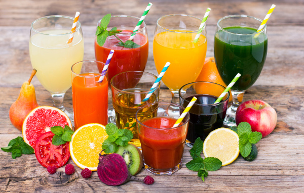 Свежевыжатые соки на столе с овощами и фруктами